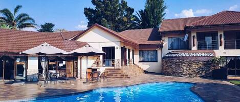 Una piscina al aire libre, sillones reclinables de piscina