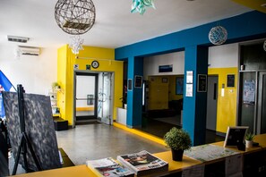 Un área de recepción con una decoración en tonos amarillo y azul, un reloj y una puerta que da a un pasillo.