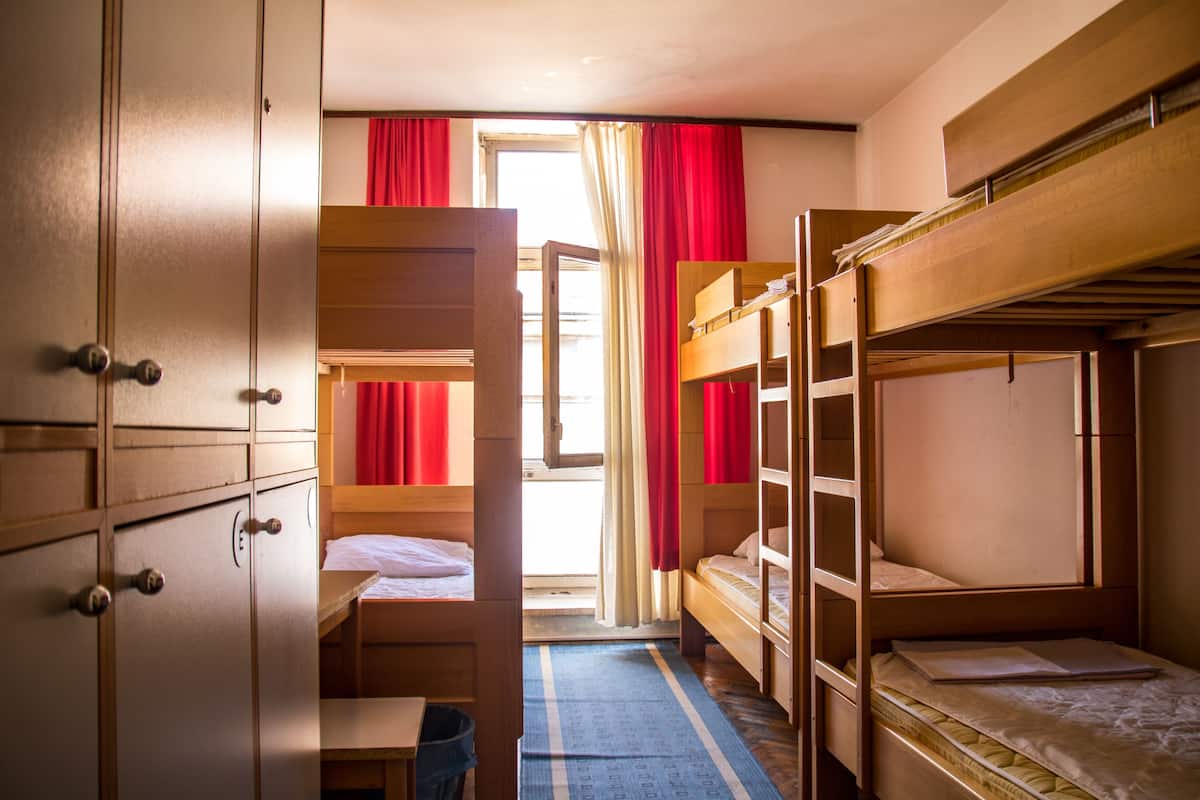 Ein Schlafsaalzimmer mit Etagenbetten, einem Schreibtisch und einem Kleiderschrank.