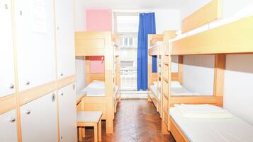 Un dormitorio con literas, una mesita pequeña y un armario.