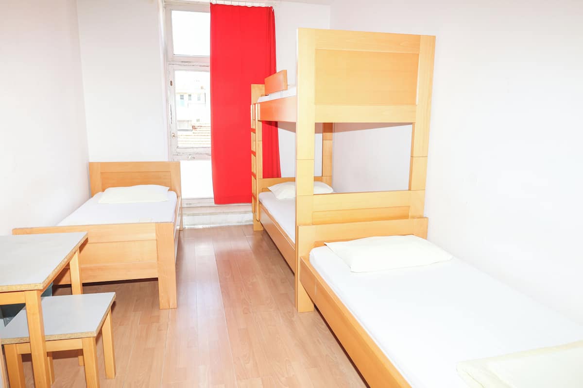 Ein Schlafsaalzimmer mit Etagenbetten, einem Schreibtisch und einem Stuhl.