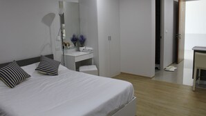 Una habitación de hotel moderna con una cama grande, una mesita de noche, un escritorio y un armario.