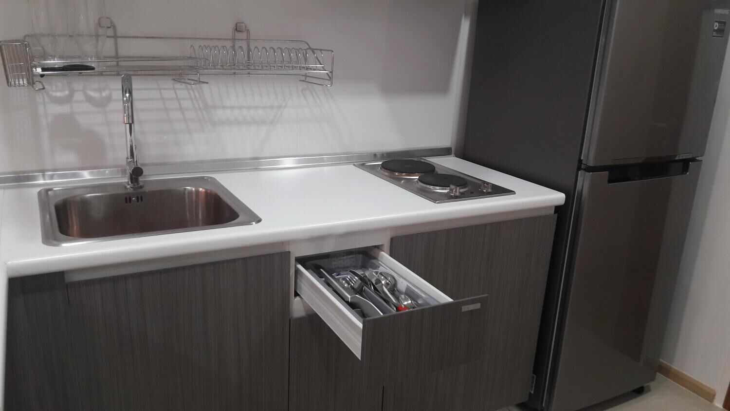 A kitchen with a stainless steel sink, a built-in stove, and a refrigerator.