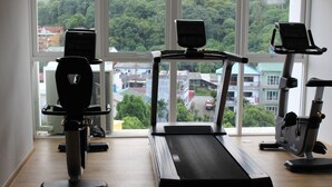 Un gimnasio con cintas de correr, bicicletas estáticas y una máquina de remo.