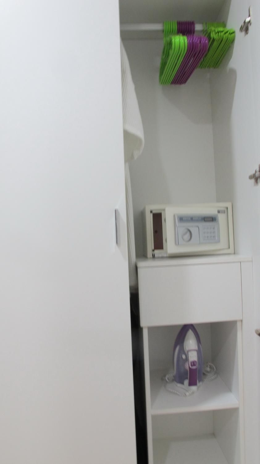 Un gabinete blanco con un microondas y un dispositivo morado sobre una repisa.
