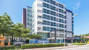 Un hotel de varios pisos con un diseño moderno, con balcones en cada planta y una señalización destacada.