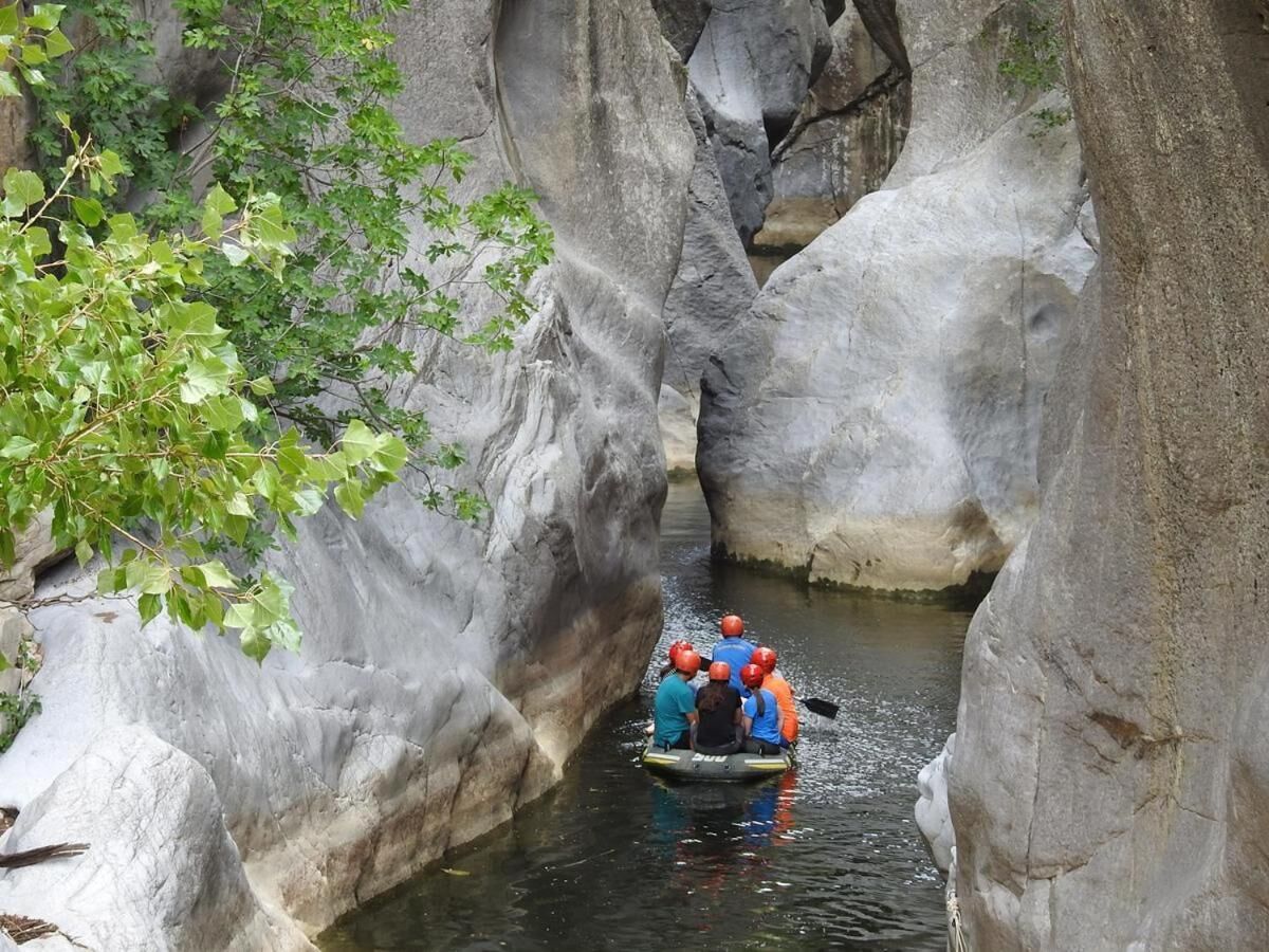 A group of people in a raft navigating a narrow water channel between large rock formations.