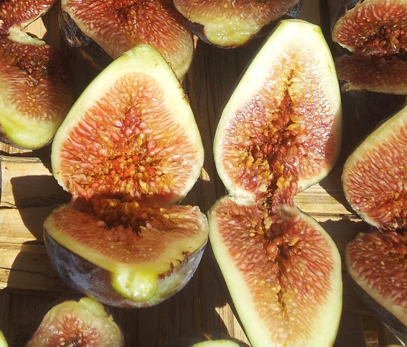 A close-up of halved figs with seeds visible, arranged on a wooden surface.