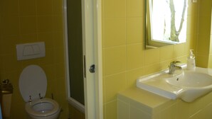 Un baño con baldosas amarillas, un lavamanos blanco y un inodoro.