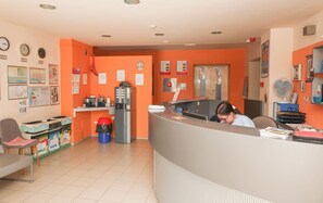 A reception area with a counter, chairs, a water dispenser, and informational posters on the walls. - HI Hostel Rijeka (Rijeka)