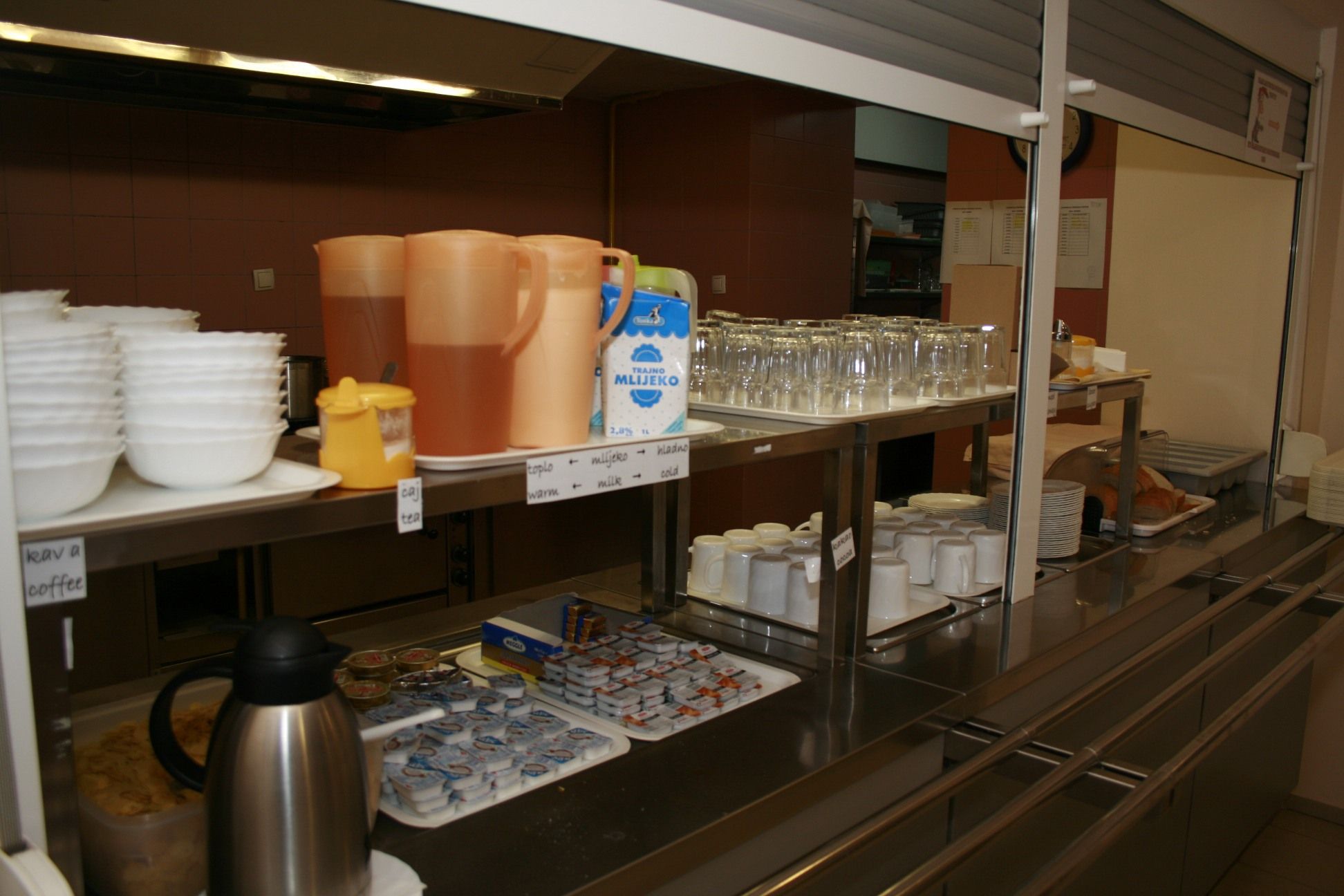 A buffet setup with various food and drink options, including coffee, tea, and milk.