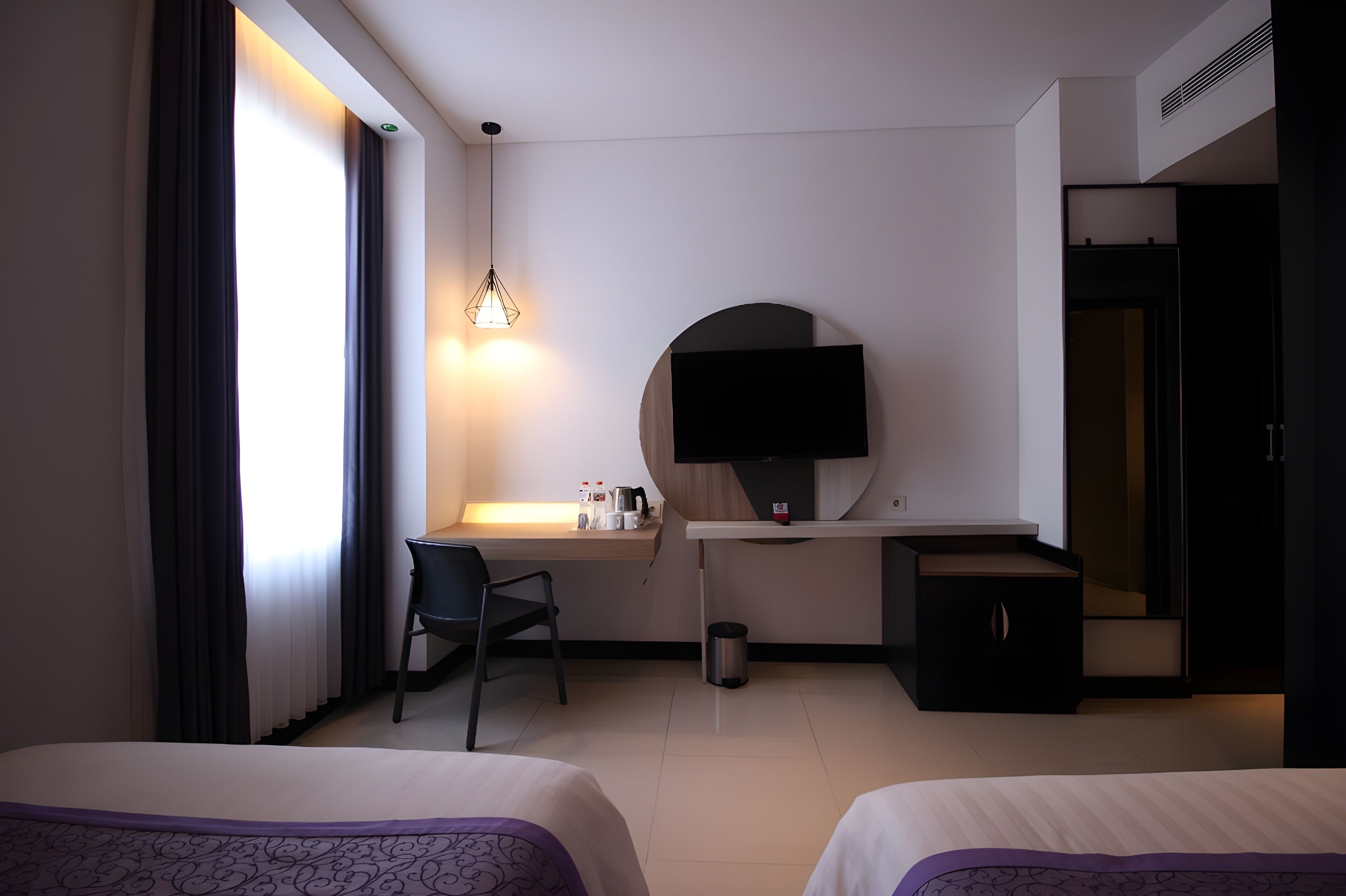A hotel room with two beds, a desk with a chair, a television, and a small cabinet.