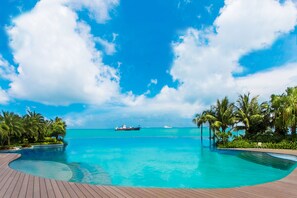 Un ciel d’un bleu limpide, une piscine et un navire au loin.