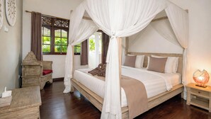 A four-poster canopy bed with a wooden headboard, a bedside table with a lamp, and a wooden chest of drawers. - Villa Bewa by Villa Finder (Seminyak)