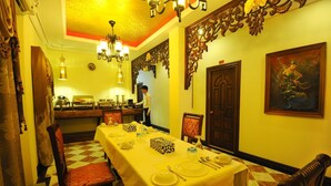 A dining area with a long table set for a meal, a chandelier, and a painting on the wall. - Union Square Hotel (Yangon)