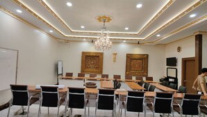 A conference room with a long table, chairs, a chandelier, and two large decorative wall panels. - Union Square Hotel (Yangon)