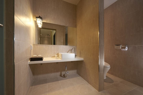 Un baño moderno con lavamanos blanco, espejo y retrete.