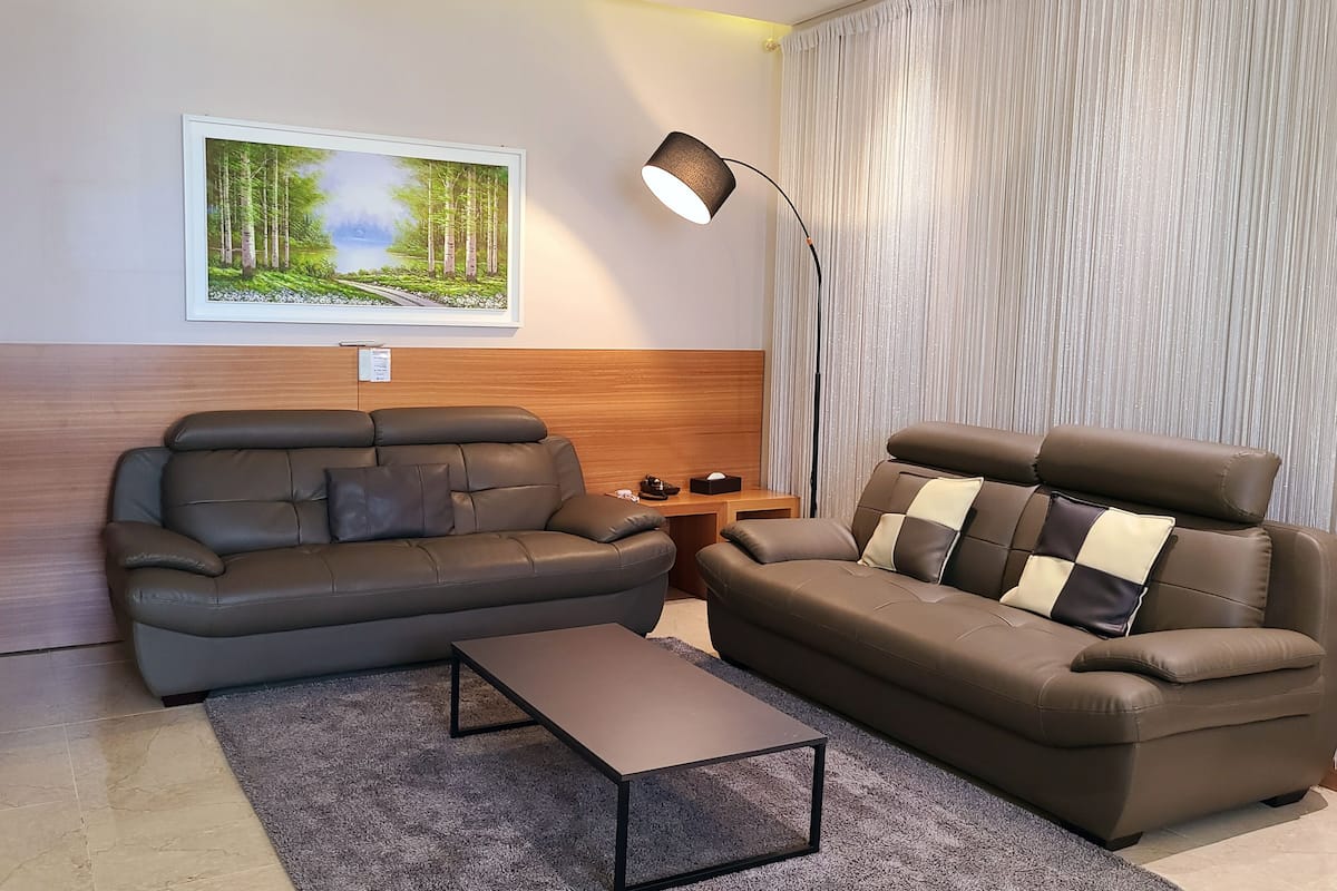 A modern living room with two sofas, a coffee table, a lamp, and a painting of a forest scene.