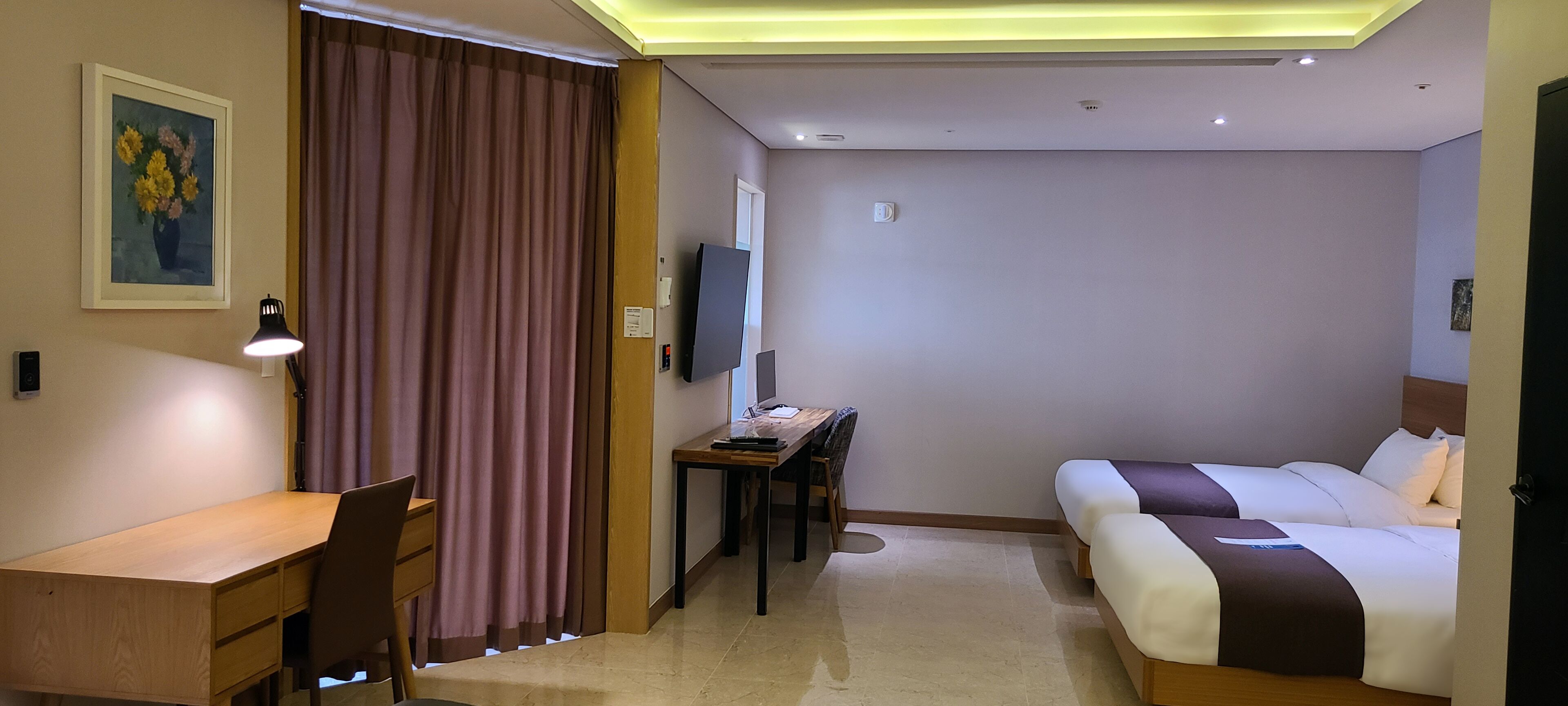 Ett hotellrum med ett skrivbord, en stol, en säng och en TV.