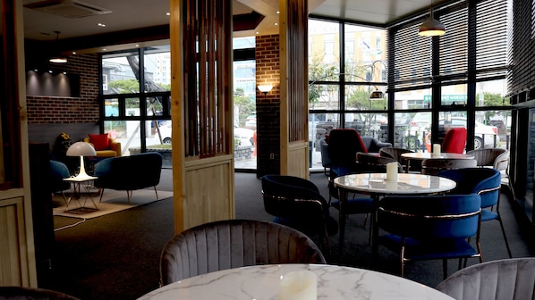 Ein Restaurant mit modernem Interieur, das Ziegelwände, große Fenster und zeitgemäße Möbel zeigt.
