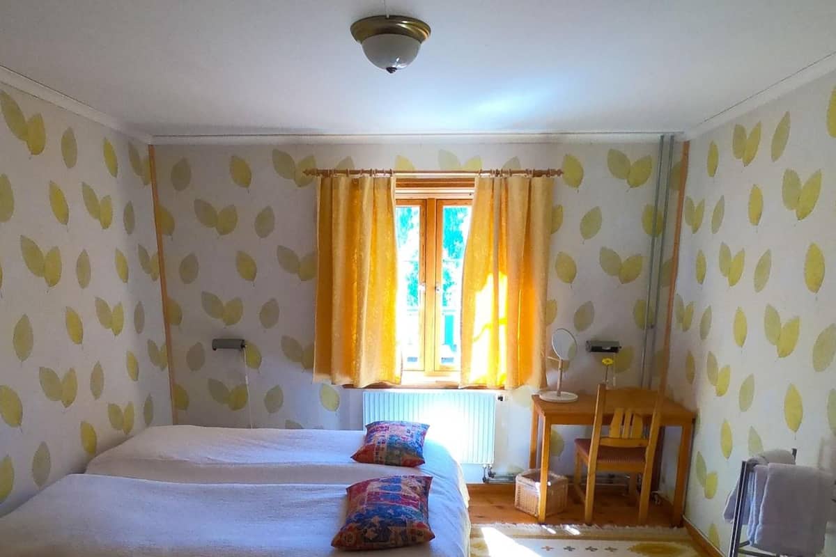 A room with a bed, a chair, a small table, and a window with curtains.