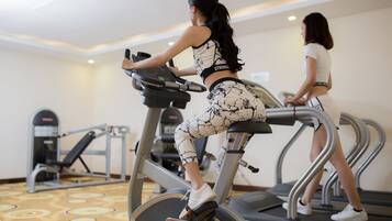 Two people using treadmills in a gym with exercise equipment in the background.