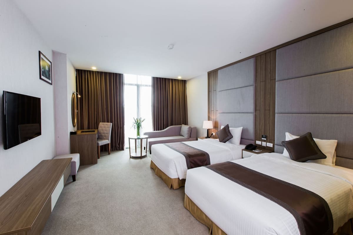 Habitación de hotel con dos camas, televisión, escritorio y silla.