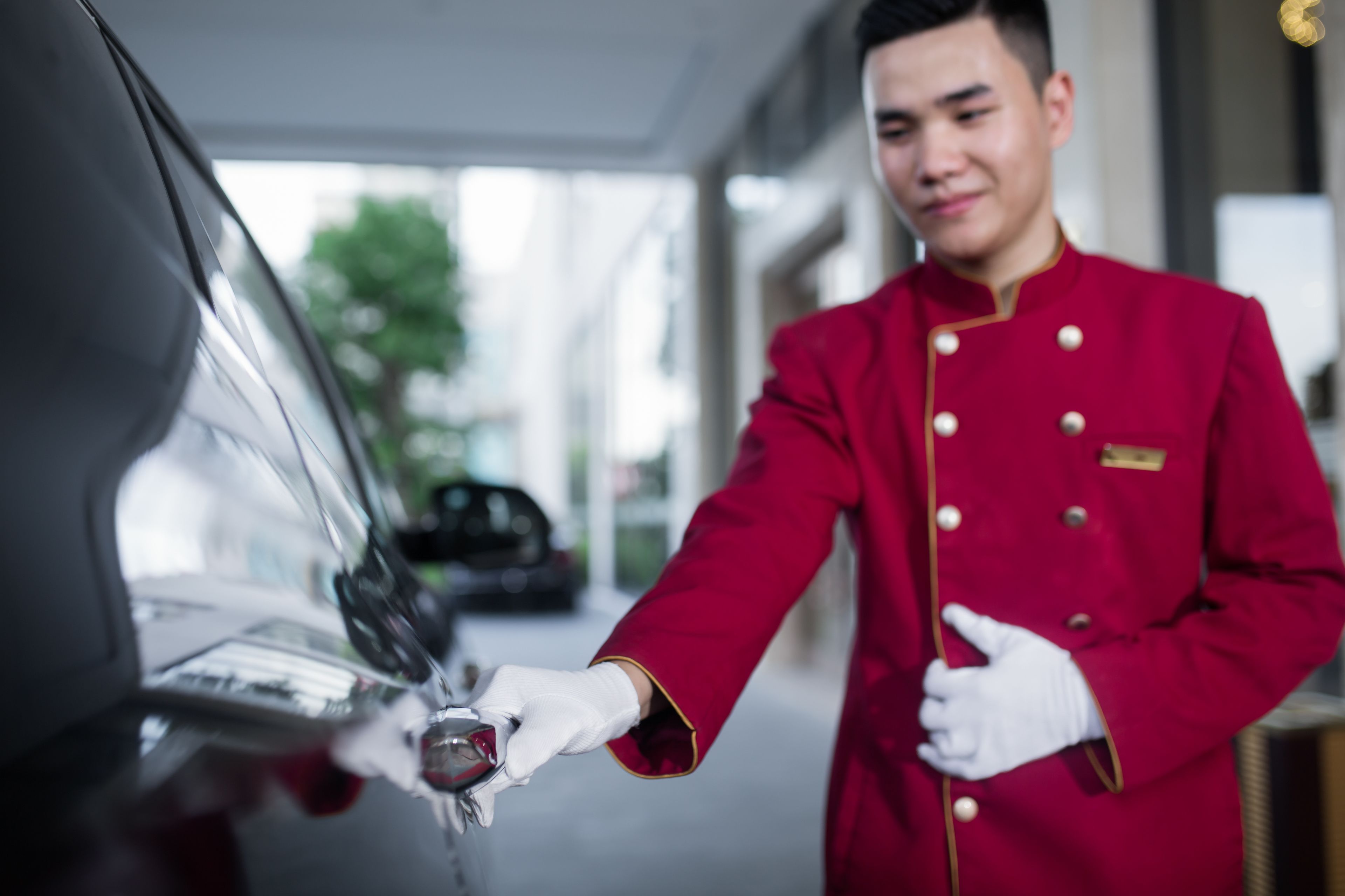 A person in a red uniform handing over a key to a car.