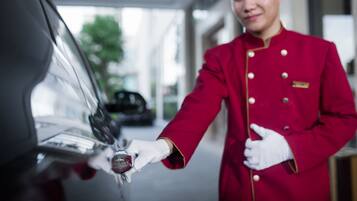 A person in a red uniform handing over a key to a car.