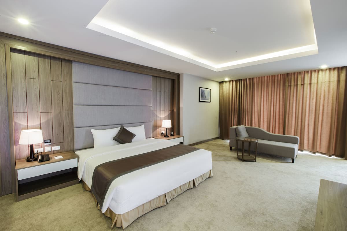 Una habitación de hotel moderna con una cama grande, un sofá y un escritorio con lámpara.