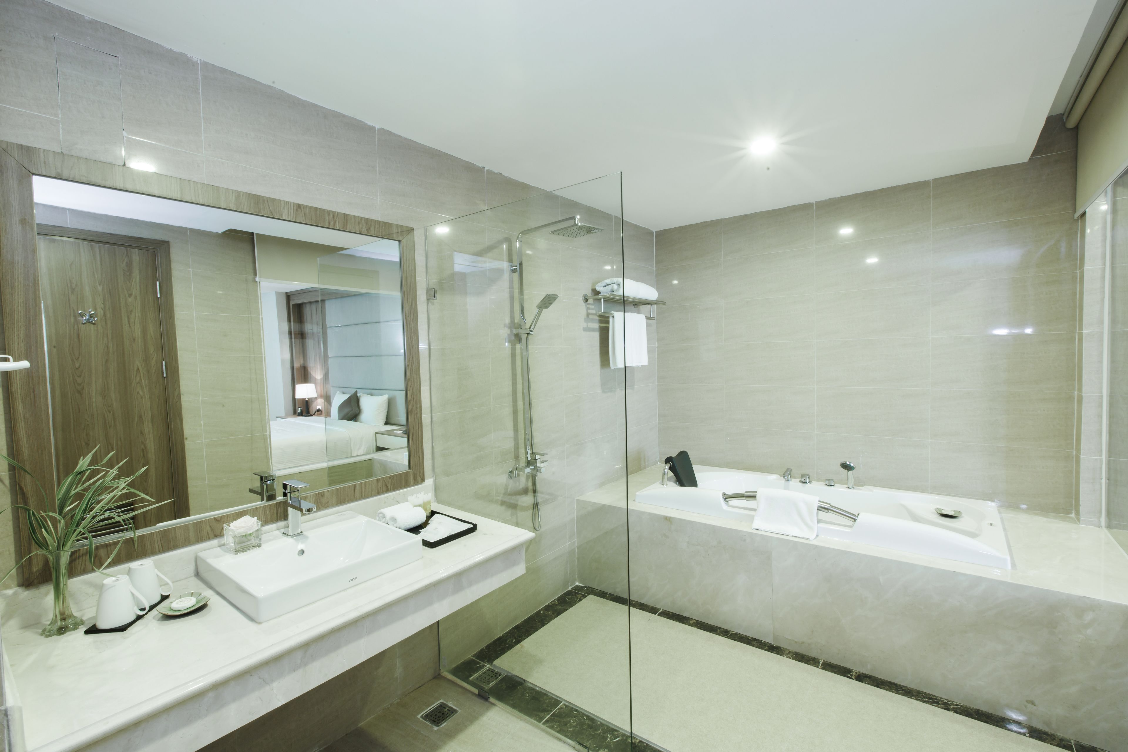 A modern bathroom with a large mirror, two sinks, a shower area, and a glass-enclosed shower.