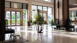 A spacious lobby with a large potted plant, seating area, and large windows allowing natural light.