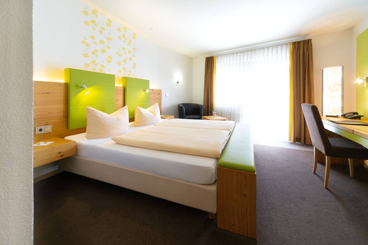 Ein Hotelzimmer mit einem großen Bett, einem Schreibtisch, einem Stuhl und einem kleinen Tisch.