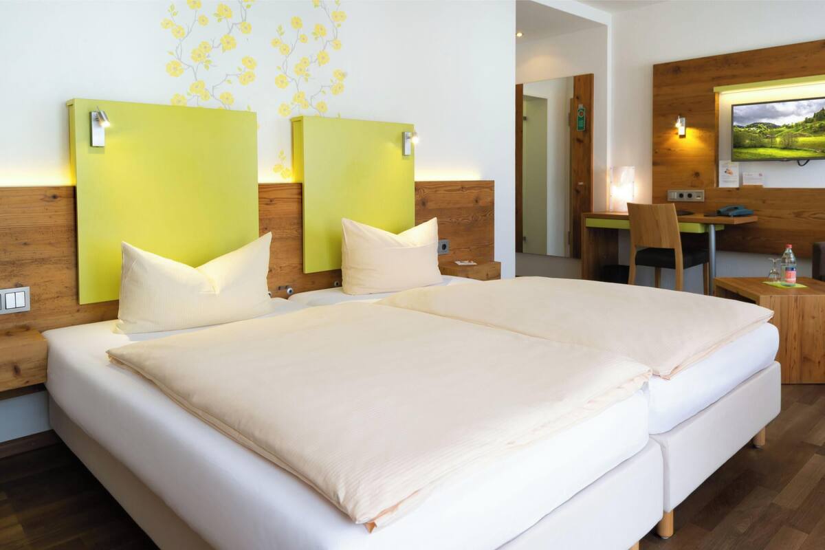Ein Hotelzimmer mit einem großen Bett, einem Schreibtisch, einem Sessel und einem Fernseher.