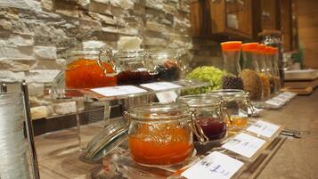 A buffet with various food items in glass jars, including jams and preserves, displayed on a counter with labels.
