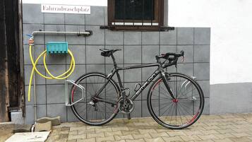 A bicycle parked against a tiled wall with a sign reading "Fahrradwaschplatz".