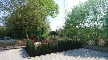 A paved walkway with a brick oven and a gazebo in a park setting.
