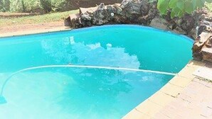 En swimmingpool med kristallklart blått vatten, omgiven av en stenmur och en gräsyta.