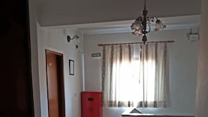 A spacious room with a wooden floor, a red cabinet, a window with curtains, and a chandelier. - Mira Tejo (Loures)