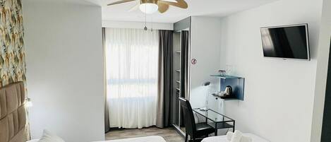 Ett hotellrum med två sängar, en takfläkt, en TV och ett skrivbord med en stol.