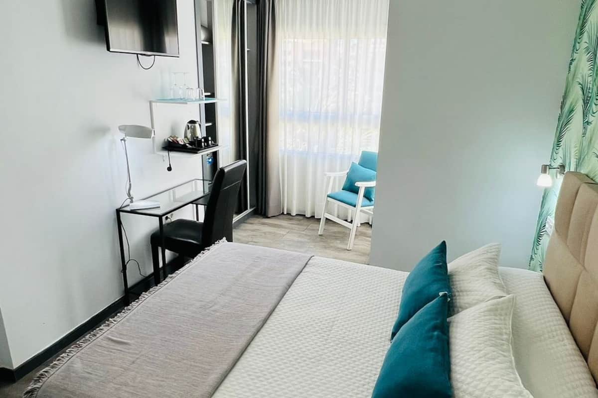 A hotel room with a bed, a desk, a chair, a TV, and a ceiling fan.