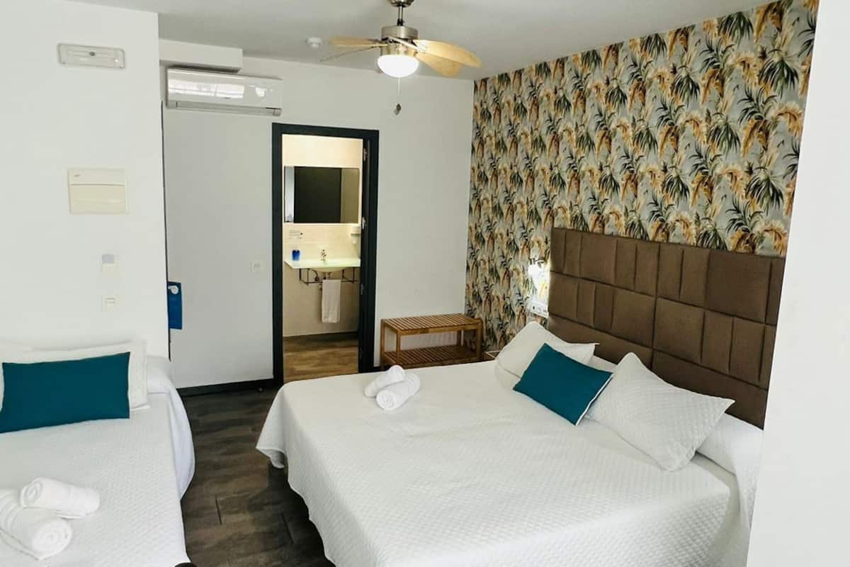 A hotel room with two beds, a desk, and a bathroom visible through an open door.