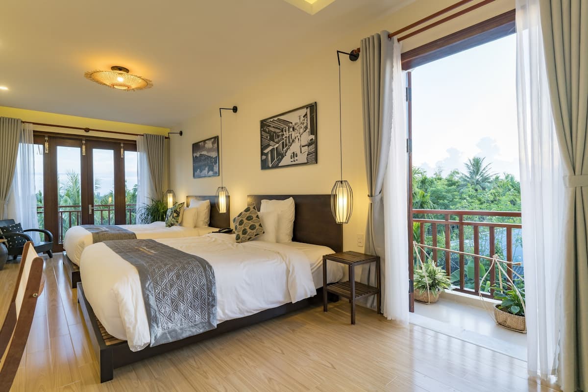 A spacious bedroom with a large bed, bedside tables, and a balcony with potted plants.