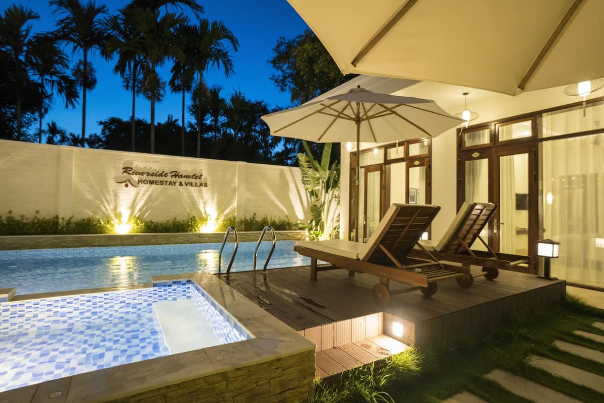 A poolside area with lounge chairs and an umbrella, surrounded by a wall with palm trees and a sign.