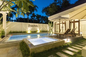 A swimming pool with a stone deck, lounge chairs, and a covered seating area with umbrellas. - Riverside Hamlet Homestay & Villas (Da Nang)