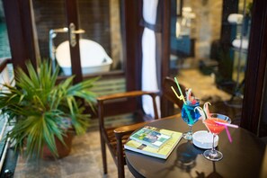 Una mesa con un libro, dos bebidas y una planta en maceta.