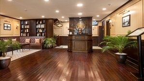 A lobby with a reception desk, seating area, and potted plants. - Orchid Trendy Cruise (Tuan Chau)
