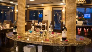 A bar area with a marble countertop, wine bottles, glasses, and a rose decoration. - Orchid Trendy Cruise (Tuan Chau)