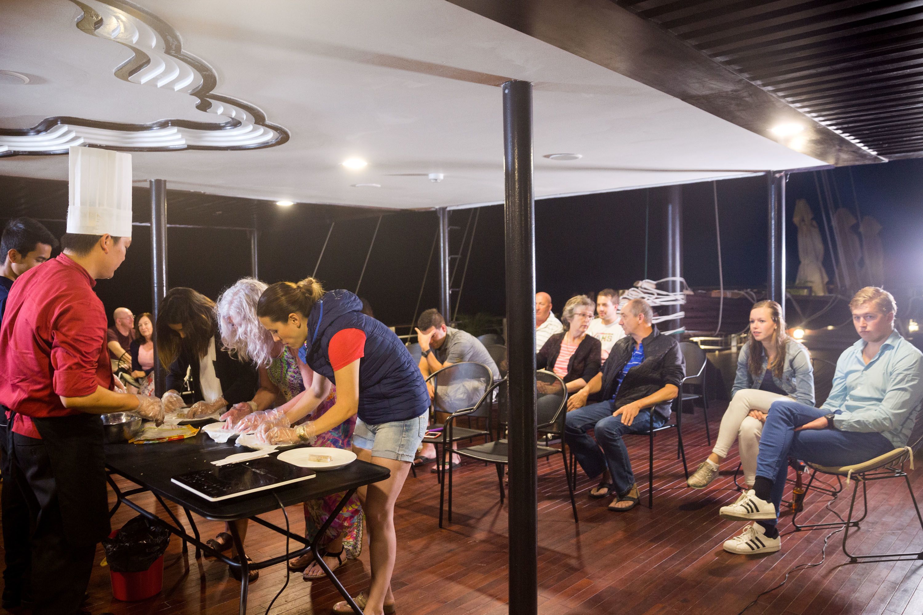 Un grupo de personas sentadas en una mesa mientras un chef prepara comida.