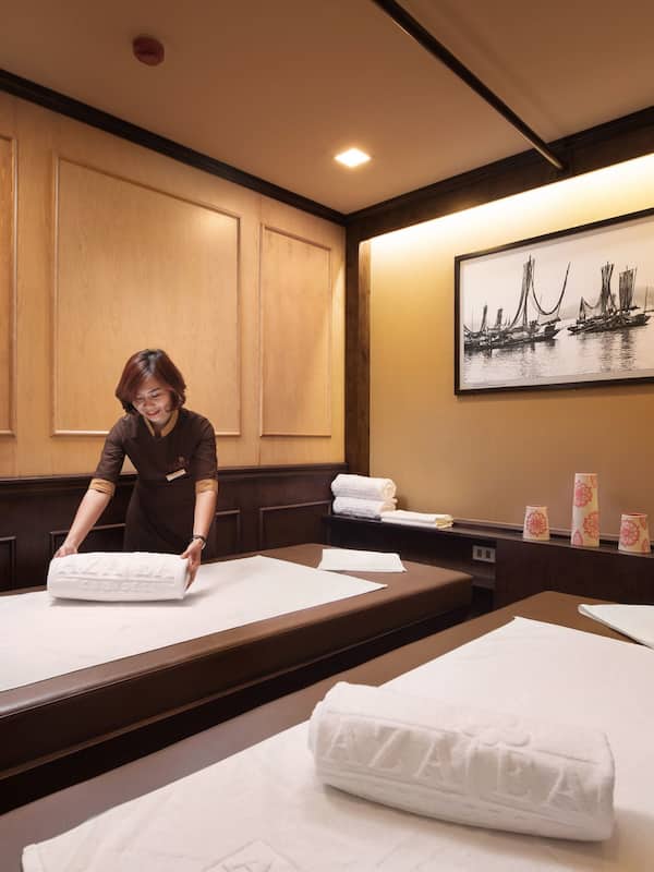 Two beds with crisp linens, a wooden bench, and a small table with a vase of flowers create a warm and inviting space.